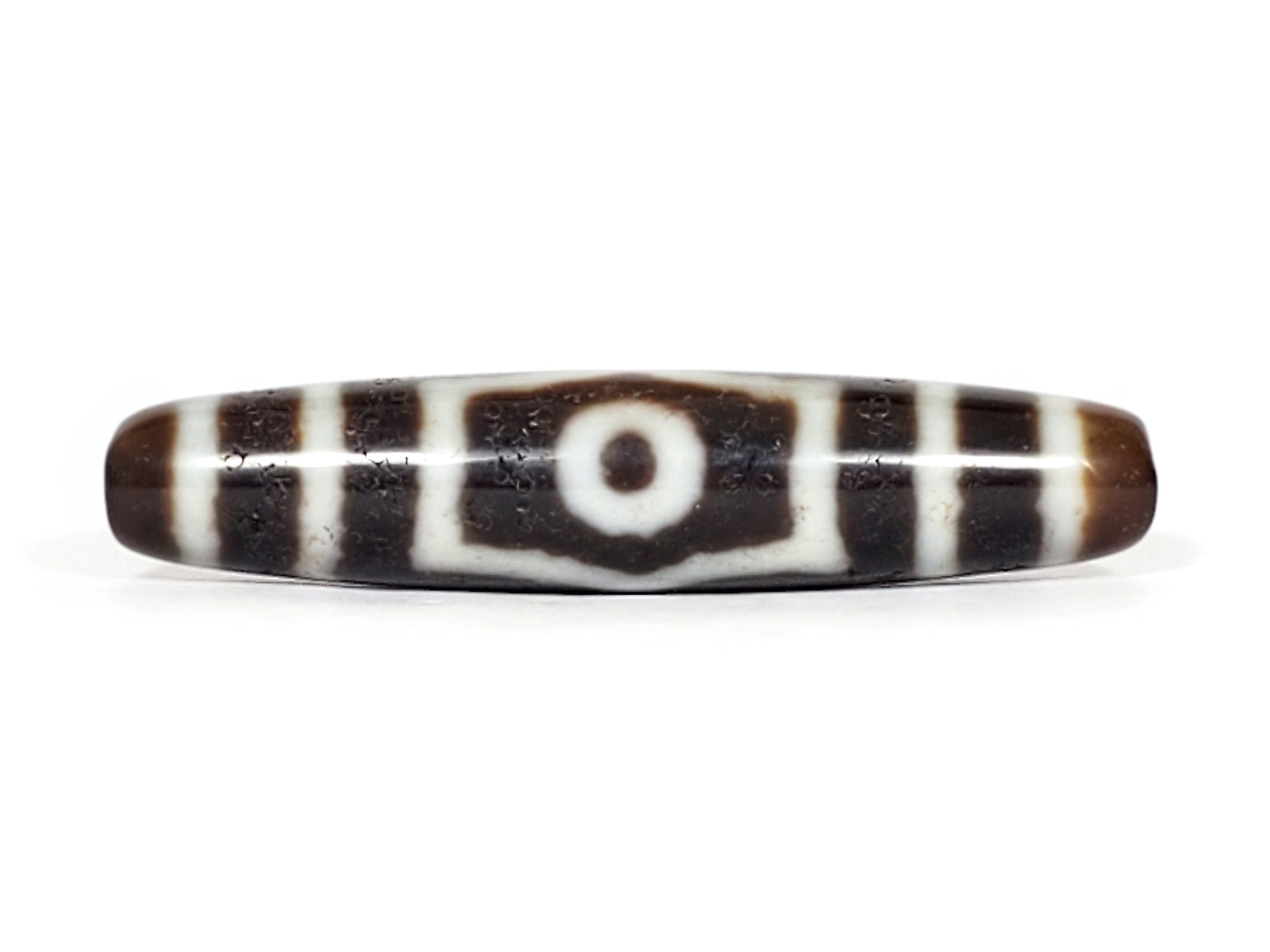 "A vintage Dzi bead featuring a captivating Three Eye Motif. This authentic artifact, identified as TD-ThE-001, showcases the intricate patterns and spiritual significance of ancient Dzi beads