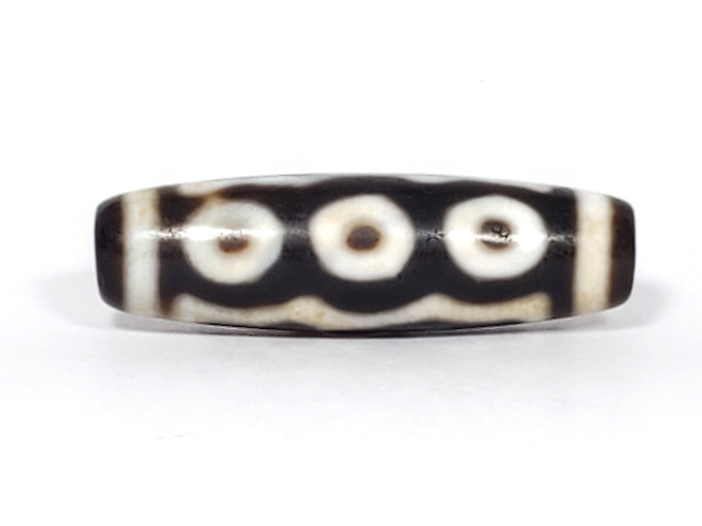 A vintage Dzi bead showcasing a beautiful Five Eye motif. The five intricately carved eyes represent wisdom, clarity, and spiritual insight. This rare and exquisite bead is a treasured piece for collectors and spiritual enthusiasts