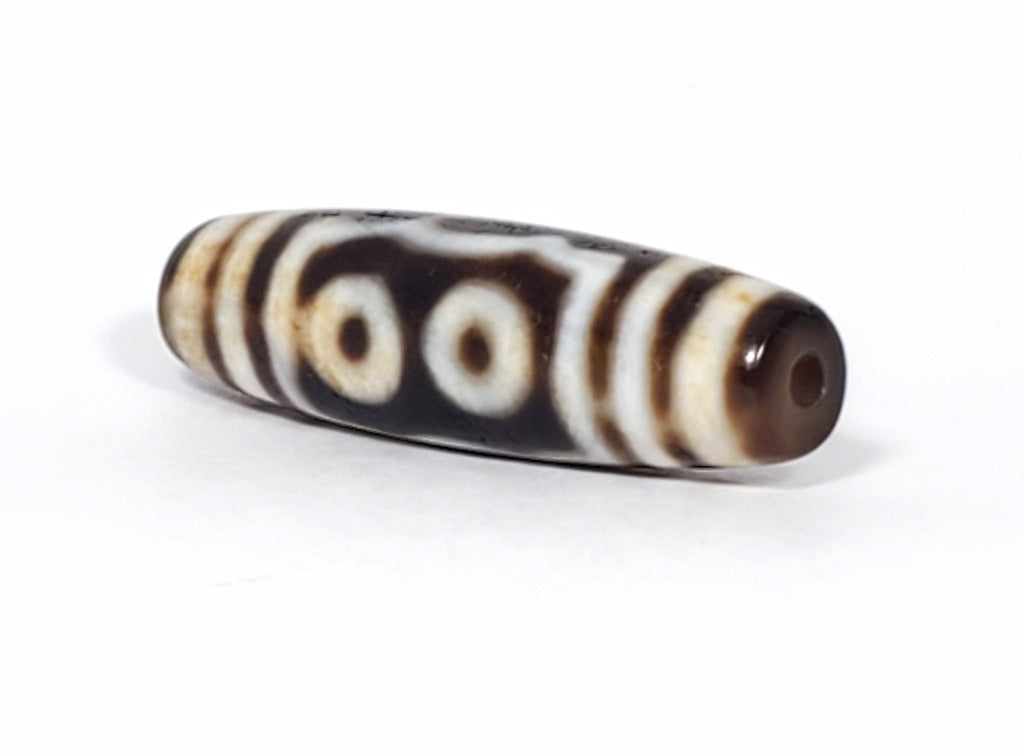 A vintage Dzi bead showcasing a beautiful Five Eye motif. The five intricately carved eyes represent wisdom, clarity, and spiritual insight. This rare and exquisite bead is a treasured piece for collectors and spiritual enthusiasts