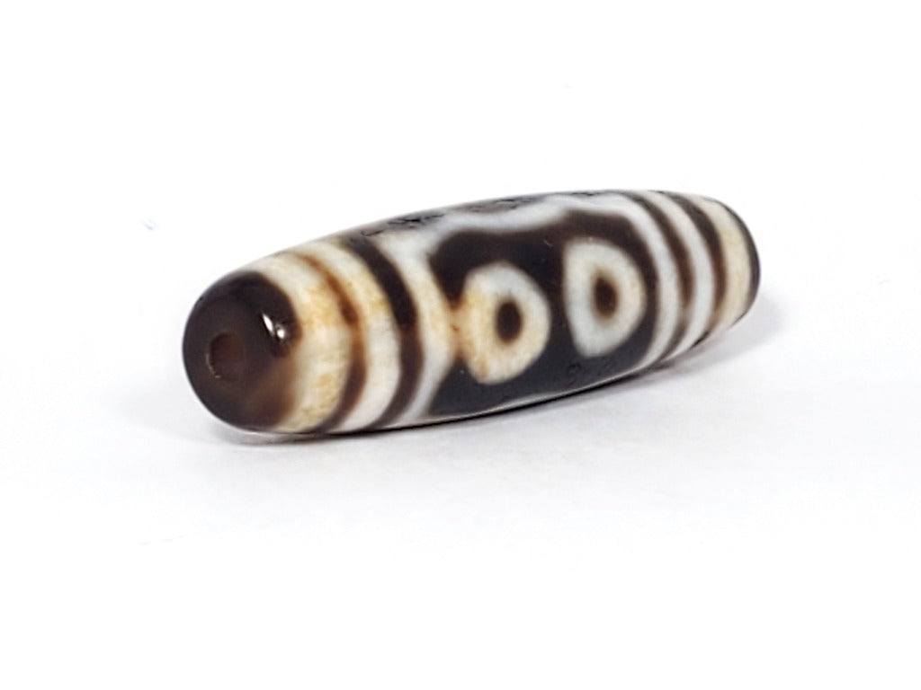 A vintage Dzi bead showcasing a beautiful Five Eye motif. The five intricately carved eyes represent wisdom, clarity, and spiritual insight. This rare and exquisite bead is a treasured piece for collectors and spiritual enthusiasts