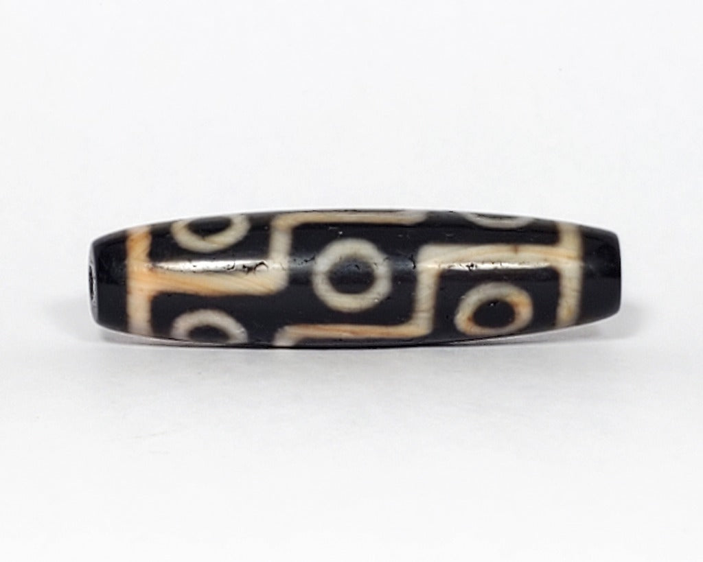 A vintage Dzi bead featuring a mesmerizing Nine Eye motif. This authentic artifact, identified as TaD-V-S-NE-052023, showcases the intricate patterns and spiritual symbolism of ancient Dzi beads