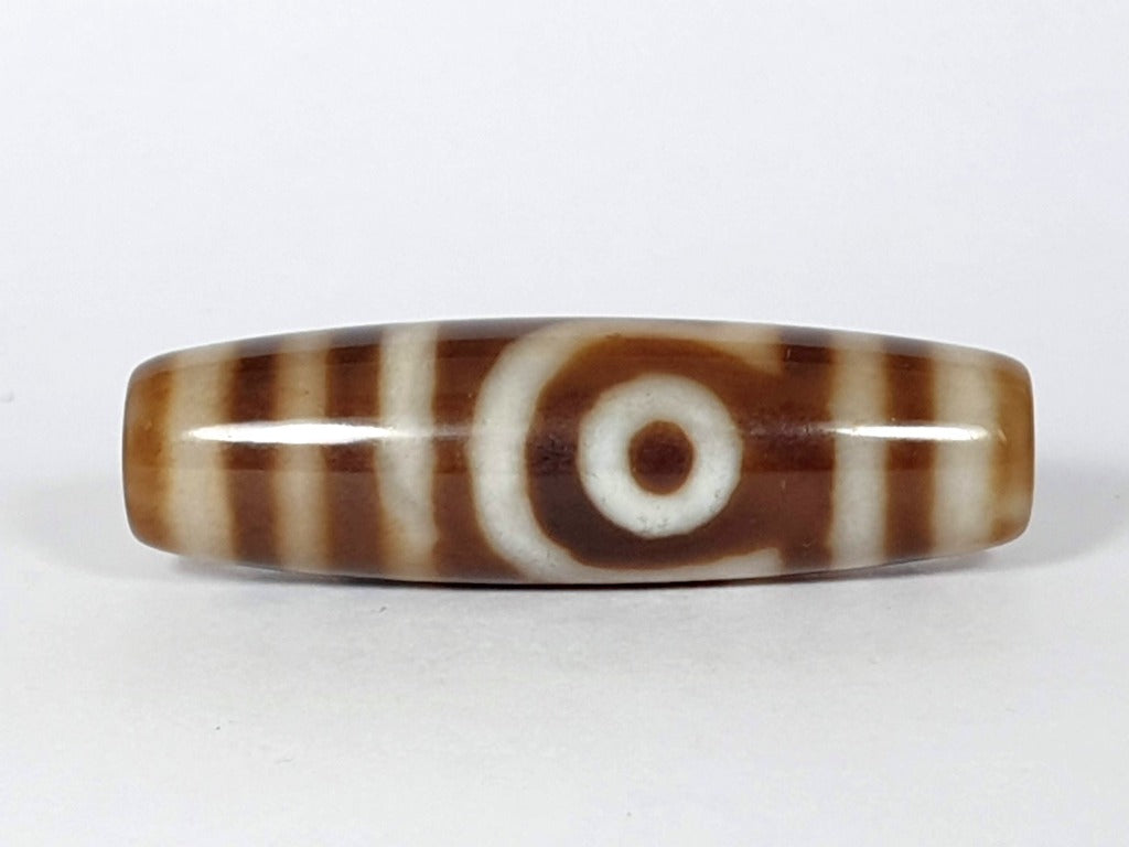 Vintage Two Eye Motif Dzi (TD-TwE-2)" Description: "A vintage Dzi bead with an enchanting Two Eye Motif. This authentic artifact, identified as TD-TwE-2, showcases the timeless beauty and cultural significance of ancient Dzi beads."