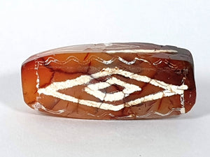  ancient Dzi bead made from Carnelian, showcasing a unique and highly sought-after Four Diamond Eye-In-Eye & Wave motif. This bead is exceptionally rare, adding to its collectability and value. The intricate design combines protective symbolism with the fluidity and power of waves, making it a remarkable piece of ancient craftsmanship and spiritual significance."