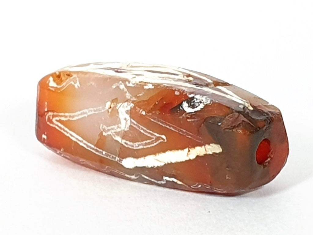  ancient Dzi bead made from Carnelian, showcasing a unique and highly sought-after Four Diamond Eye-In-Eye & Wave motif. This bead is exceptionally rare, adding to its collectability and value. The intricate design combines protective symbolism with the fluidity and power of waves, making it a remarkable piece of ancient craftsmanship and spiritual significance."