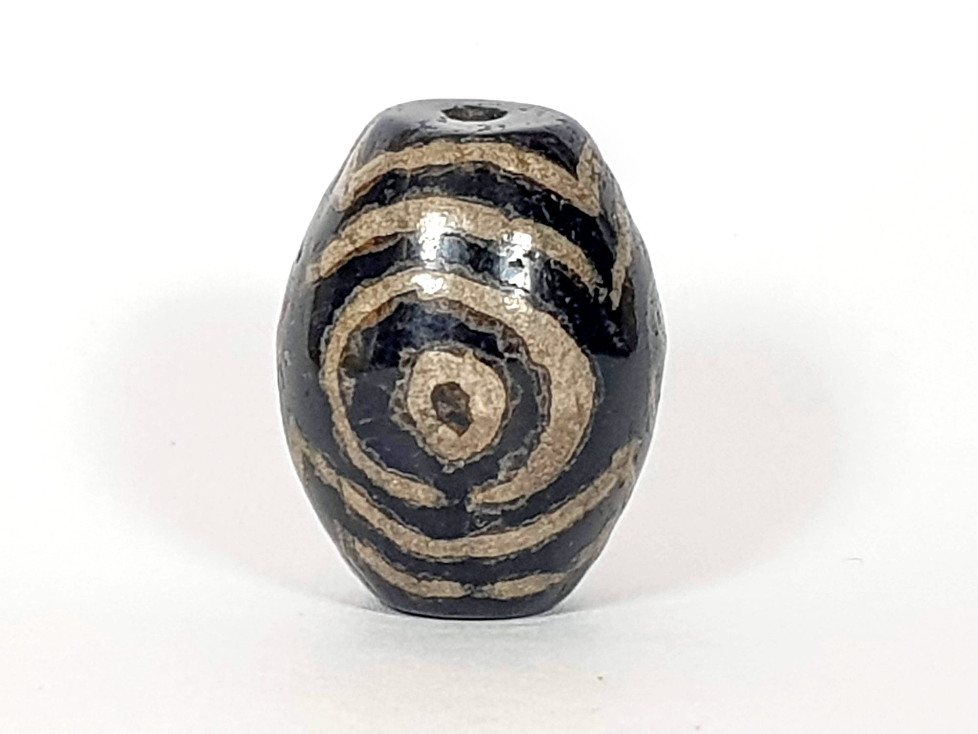 ancient Indus Valley dzi bead adorned with the triple heaven's gate motif.