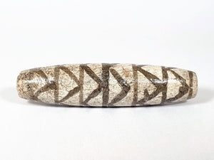 A vintage Dzi bead with a faux antique appearance featuring a captivating white tiger tooth and stripes motif. The bead showcases intricate carvings resembling the patterns found on a tiger's tooth, symbolizing strength, courage, and protection. This unique and beautifully crafted bead is a must-have for collectors and enthusiasts of ancient-inspired jewelry.