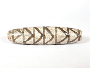 A vintage Dzi bead with a faux antique appearance featuring a captivating white tiger tooth and stripes motif. The bead showcases intricate carvings resembling the patterns found on a tiger's tooth, symbolizing strength, courage, and protection. This unique and beautifully crafted bead is a must-have for collectors and enthusiasts of ancient-inspired jewelry.