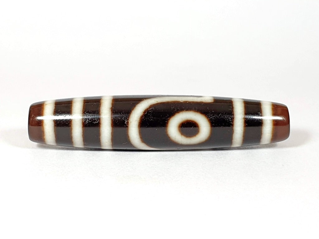 A vintage Dzi bead with a unique Two Eye Motif. This authentic artifact carries historical significance and showcases the captivating design of ancient Dzi beads