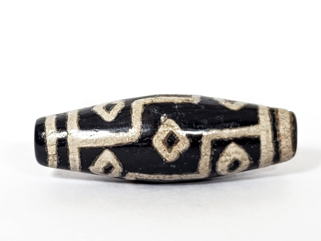 A vintage Dzi bead with a faux antique appearance featuring a captivating nine-eye motif. The intricate patterns and aged texture give it a sense of ancient mystique and cultural significance. The nine eyes symbolize protection, wisdom, and spiritual enlightenment