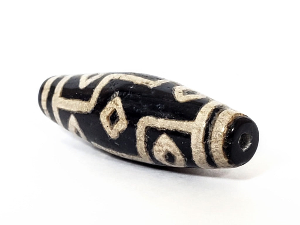 A vintage Dzi bead with a faux antique appearance featuring a captivating nine-eye motif. The intricate patterns and aged texture give it a sense of ancient mystique and cultural significance. The nine eyes symbolize protection, wisdom, and spiritual enlightenment