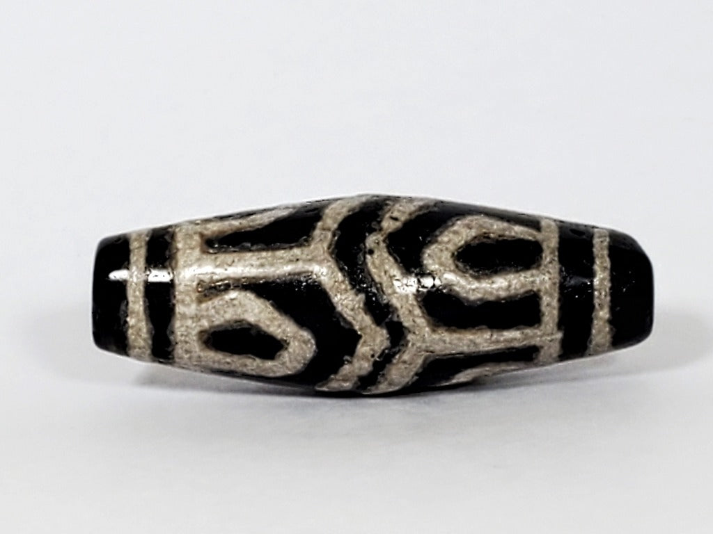 A vintage Dzi bead with a faux antique appearance featuring a beautiful six-eye lotus motif. The bead showcases intricate carvings resembling the delicate petals of a lotus flower, with six eyes symbolizing wisdom and insight. This unique bead exudes a sense of elegance and spirituality, making it a captivating addition to any jewelry collection