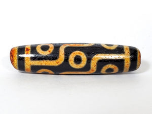 A vintage Dzi bead with a faux antique appearance featuring a captivating nine-eye motif. The bead exhibits intricate carvings and an aged texture, reminiscent of ancient artifacts with deep spiritual significance. The nine eyes symbolize protection, wisdom, and spiritual insight