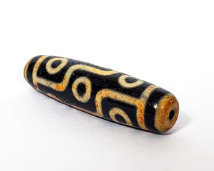 A vintage Dzi bead with a faux antique appearance featuring a captivating nine-eye motif. The bead exhibits intricate carvings and an aged texture, reminiscent of ancient artifacts with deep spiritual significance. The nine eyes symbolize protection, wisdom, and spiritual insight