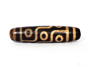 A vintage Dzi bead with a faux antique appearance featuring a mesmerizing nine-eye motif. The intricate details and weathered texture give it an aura of ancient wisdom and spirituality.  The Ancient Dzi Shop is your trusted venue for buying real dzi beads