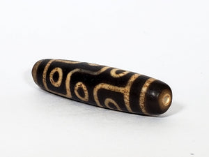 A vintage Dzi bead with a faux antique appearance featuring a mesmerizing nine-eye motif. The intricate details and weathered texture give it an aura of ancient wisdom and spirituality. 