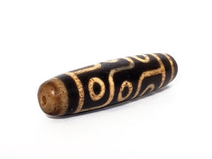 A vintage Dzi bead with a faux antique appearance featuring a mesmerizing nine-eye motif. The intricate details and weathered texture give it an aura of ancient wisdom and spirituality. 