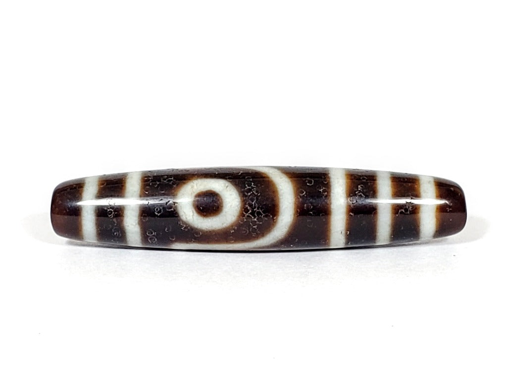 A vintage Dzi bead with a captivating Two Eye Motif. This authentic artifact showcases the timeless beauty and cultural significance of ancient Dzi bead