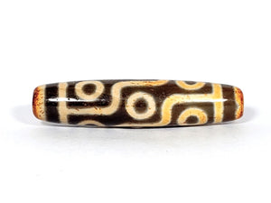 A vintage Dzi bead with a faux antique appearance featuring a captivating nine-eye motif. The bead showcases intricate carvings and a weathered texture, evoking a sense of ancient mystique and spiritual significance