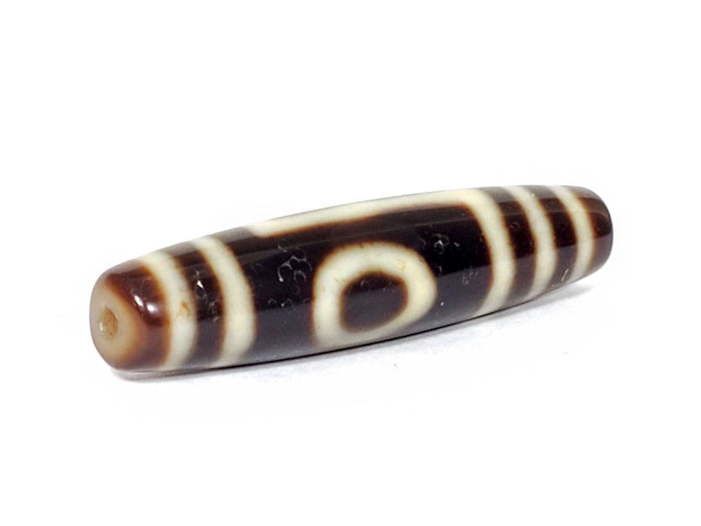 A vintage Dzi bead featuring a captivating One Eye & Mountain motif. This authentic artifact, identified as TD-OEM-1, showcases the intricate patterns and spiritual symbolism of ancient Dzi beads