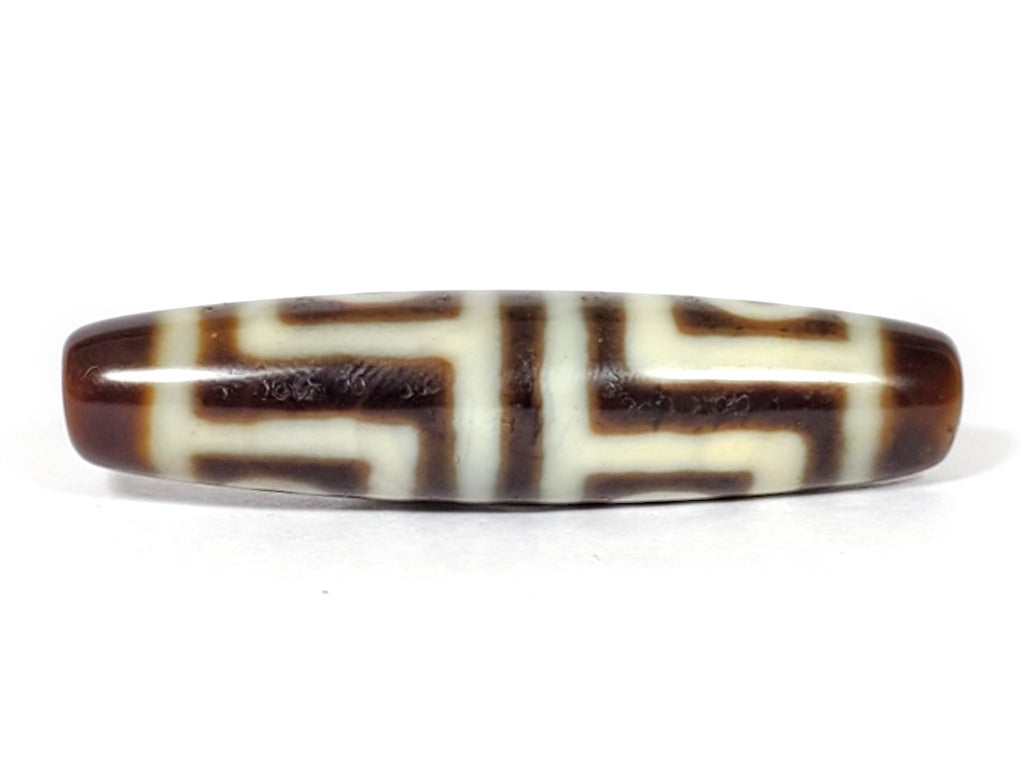 A vintage Dzi bead featuring a stunning Four Eye motif. The intricately carved eyes symbolize protection and spiritual insight. This exquisite bead is a prized collectible for Dzi bead enthusiasts.