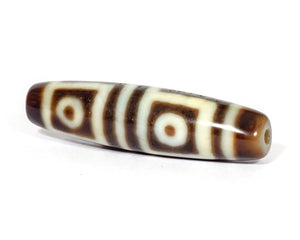 A vintage Dzi bead featuring a stunning Four Eye motif. The intricately carved eyes symbolize protection and spiritual insight. This exquisite bead is a prized collectible for Dzi bead enthusiasts.