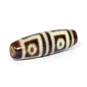 A vintage Dzi bead featuring a stunning Four Eye motif. The intricately carved eyes symbolize protection and spiritual insight. This exquisite bead is a prized collectible for Dzi bead enthusiasts.