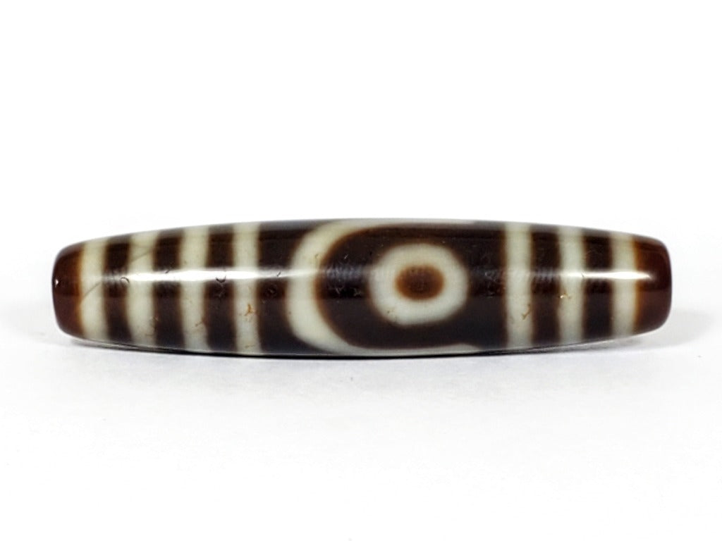 A vintage Dzi bead featuring a unique Two Eye Motif and a rare Triple Bar design. This rare find showcases the intricate craftsmanship and symbolic beauty of ancient Dzi beads