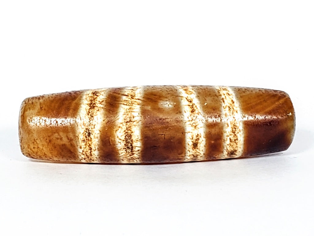  "Authentic and rare old Tibetan Seven Stripe Motif Dzi Bead, showcasing its unique design and cultural significance."