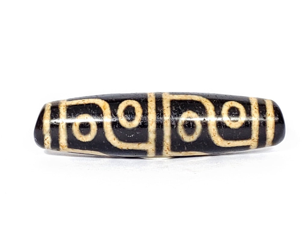 A vintage Dzi bead featuring a captivating Twelve Eye Motif. This authentic artifact embodies the rich history and symbolic significance of ancient Dzi beads