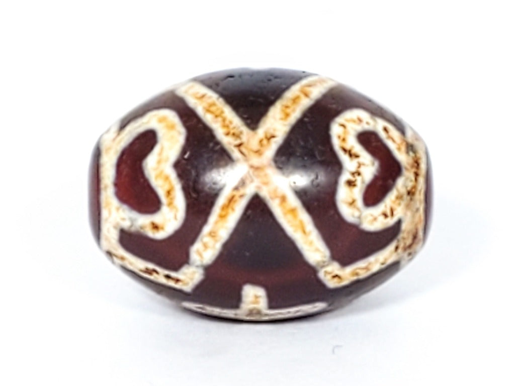 A vintage Dzi bead featuring a round shape adorned with a captivating Four Eye Lotus & Cross motif. This authentic artifact, identified as R-FoELC, showcases the intricate patterns and spiritual symbolism of ancient Dzi beads