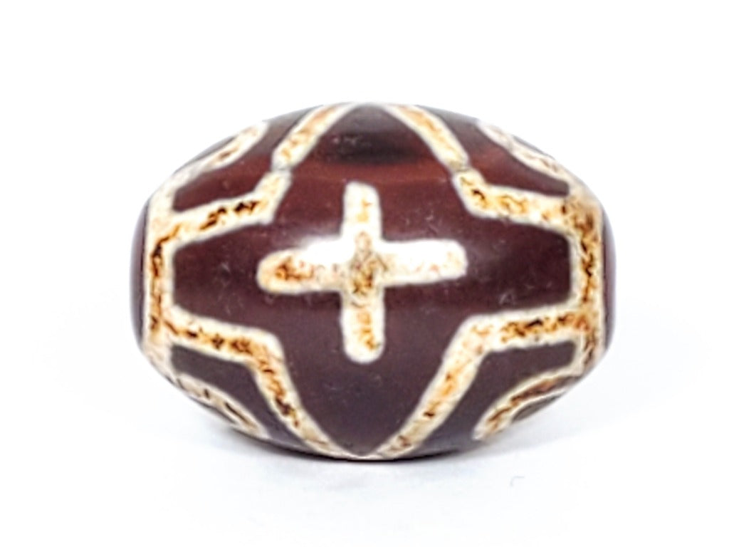 A vintage Dzi bead featuring a round shape adorned with a captivating Four Eye Lotus & Cross motif. This authentic artifact, identified as R-FoELC, showcases the intricate patterns and spiritual symbolism of ancient Dzi beads