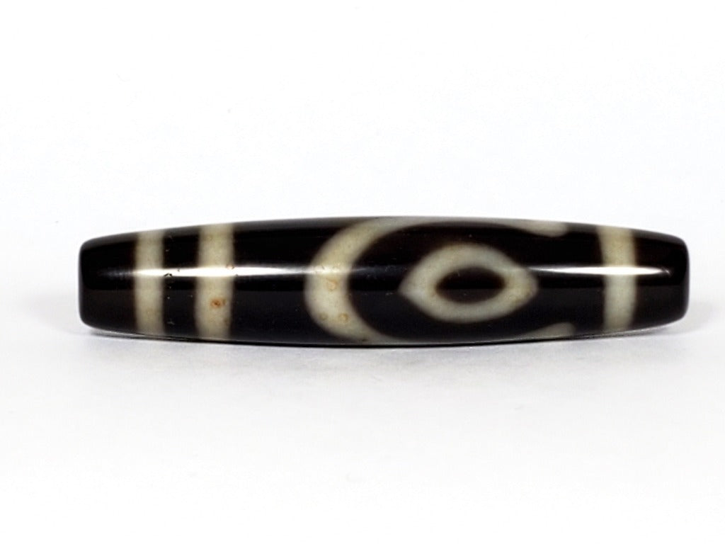 A vintage Dzi bead featuring a unique and rare variant of the Four Eye motif. This intricately carved bead showcases four eyes and carries deep spiritual significance. A collector's item with distinctive beauty