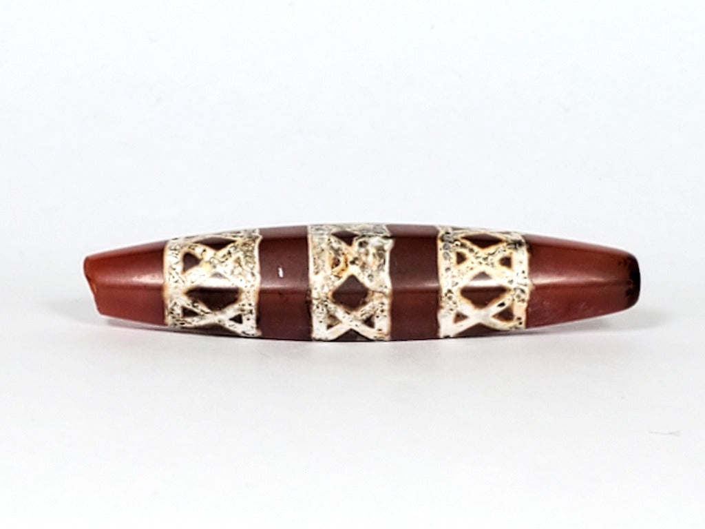 Genuine ancient Dzi bead featuring an intricate criss cross motif in captivating carnelian. Its unique hexagon shape adds to its historical charm.