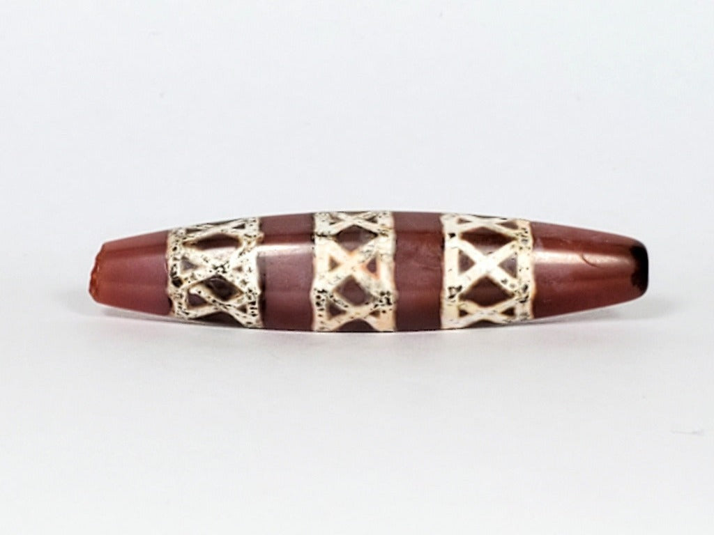 Genuine ancient Dzi bead featuring an intricate criss cross motif in captivating carnelian. Its unique hexagon shape adds to its historical charm.