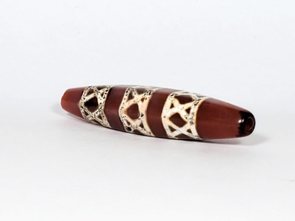 Genuine ancient Dzi bead featuring an intricate criss cross motif in captivating carnelian. Its unique hexagon shape adds to its historical charm.