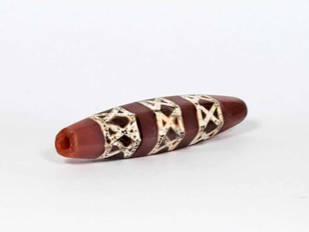 Genuine ancient Dzi bead featuring an intricate criss cross motif in captivating carnelian. Its unique hexagon shape adds to its historical charm.