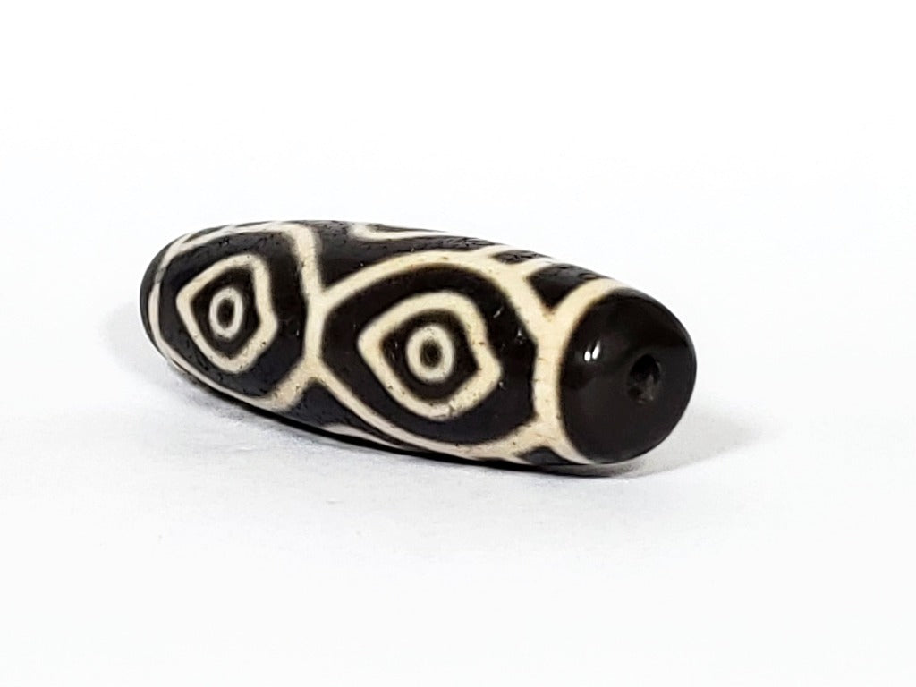 Vintage Dragon Eye Dzi Bead" Description: "A mesmerizing vintage Dzi bead featuring a captivating dragon eye motif. The intricate details and vibrant colors of the bead create an aura of mystique and power