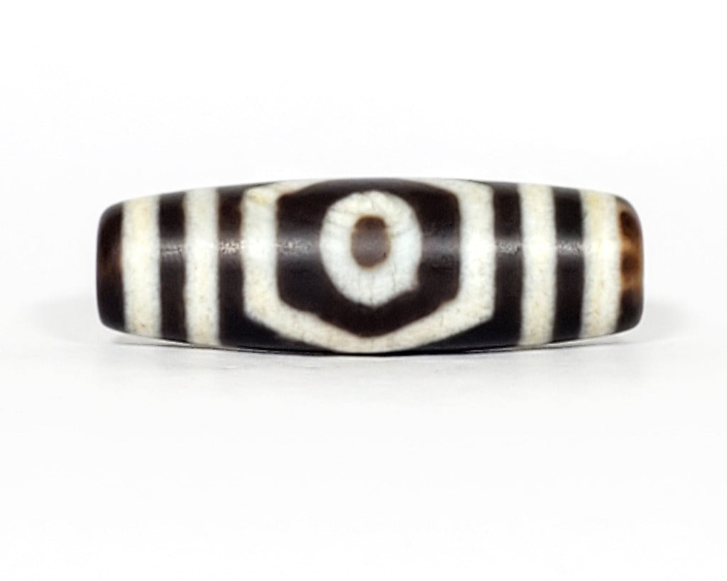 A vintage Dzi bead featuring a mesmerizing Three Eye Motif. This authentic artifact, identified as TaD-ThE-1, showcases the intricate craftsmanship and spiritual significance of ancient Dzi beads