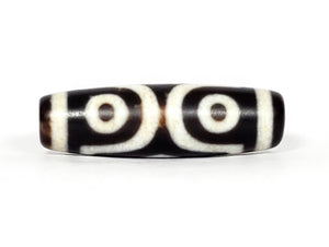 A vintage Dzi bead featuring a mesmerizing Three Eye Motif. This authentic artifact, identified as TaD-ThE-1, showcases the intricate craftsmanship and spiritual significance of ancient Dzi beads