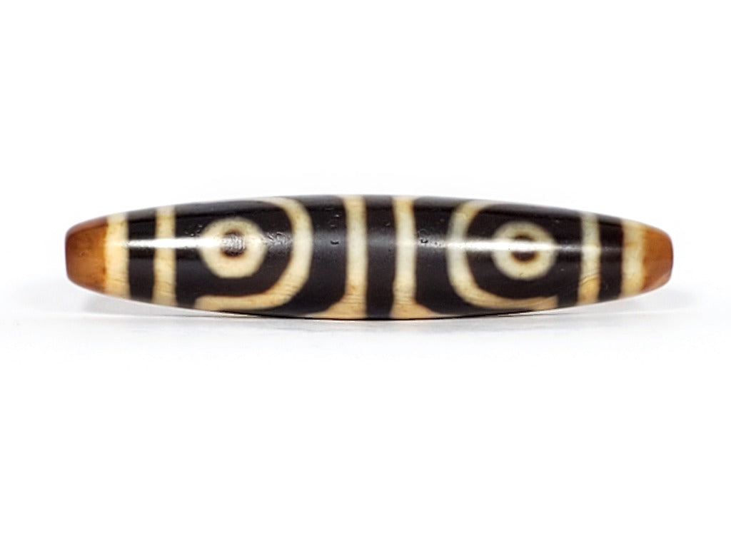 ancient Dzi bead adorned with a powerful Four Eye & Tiger Tooth motif. This bead carries deep spiritual symbolism, representing enhanced perception, inner strength, and protection. The Four Eye motif symbolizes heightened spiritual vision, while the Tiger Tooth motif embodies courage and warding off negative energies