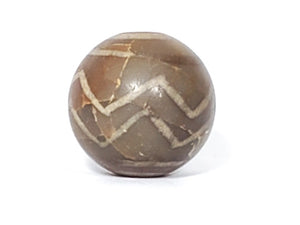 Ancient Round Double Wave Motif Dzi Bead. An authentic ancient round Dzi bead featuring a stunning Double Wave motif. This Dzi bead is a true reflection of the skilled craftsmanship and artistic expression of Tibetan artisans