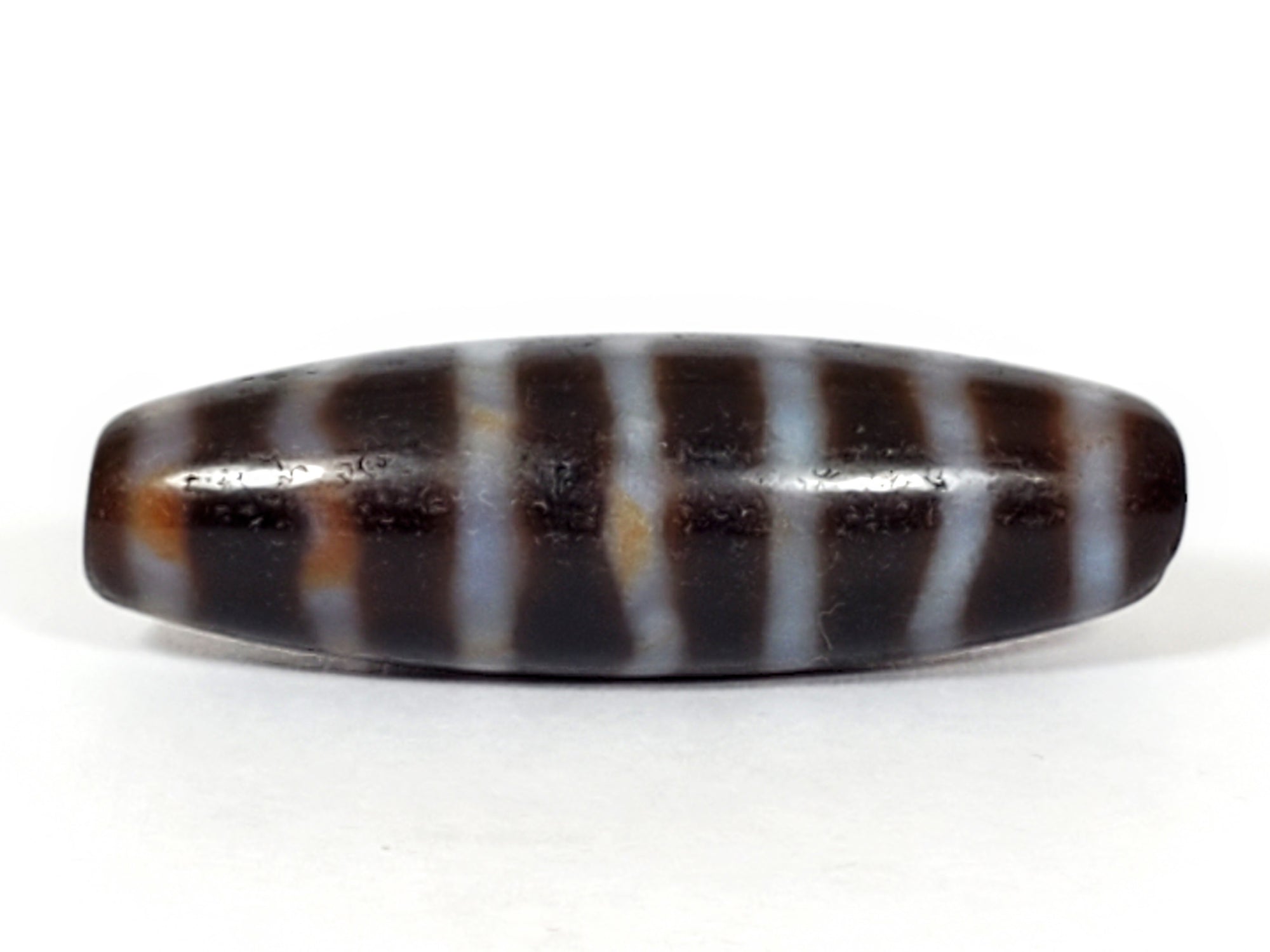 this dzi bead is adorned with the wave and stripe motif.  